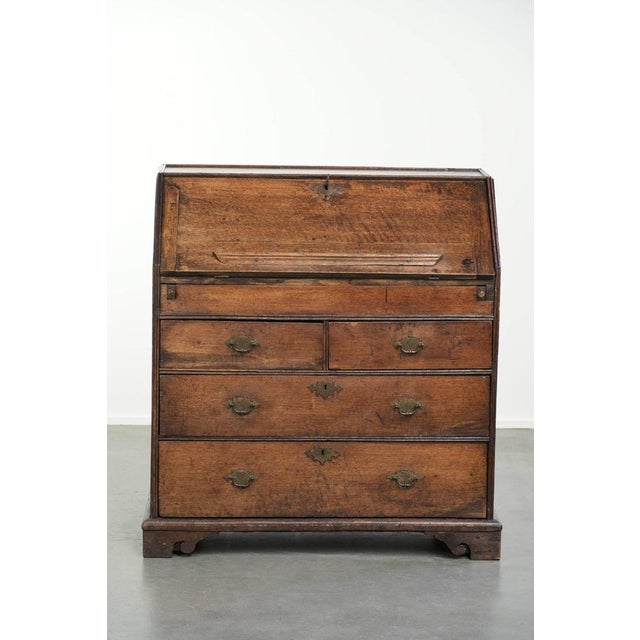 This beautiful antique English oak secretary desk from the early 18th century features a graceful and elegantly curved...