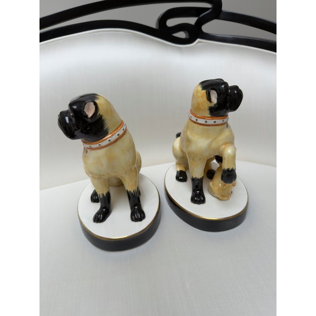 Charming pug dogs on pedestal bases with grumpy expressions in fine ceramic by esteemed design firm Chelsea House -...