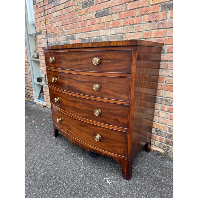 This item is a Regency or George III bow-front mahogany chest of drawers.Bow Front: The distinctive convex curve of the...