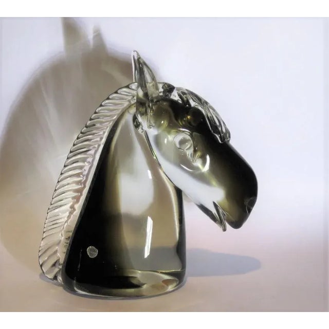 Offered for sale is a large sculpture of a horse head in solid glass with shades of grey/smoky and transparent glass. The...