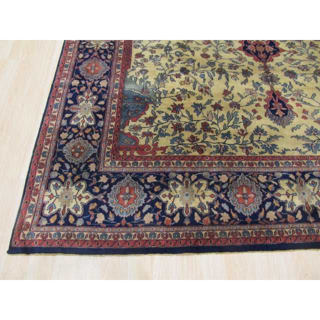 An 8' 10" x 11' 1" hand-knotted wool rug with an ivory field of dense floral vines around a central medallion, framed by a...