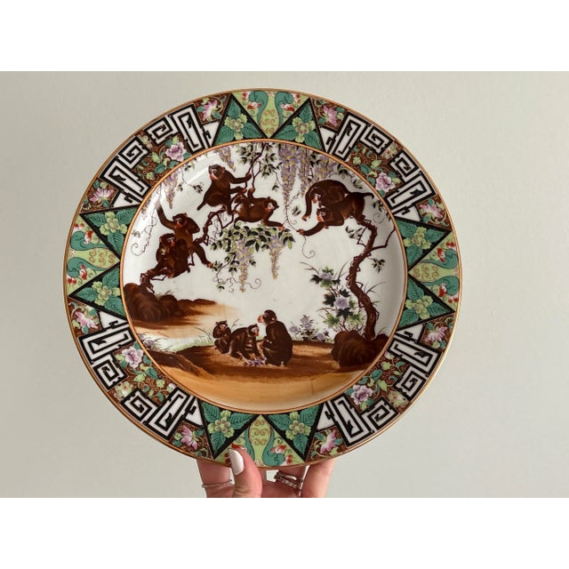 This vintage Chinese porcelain plate features a lively and detailed scene of monkeys climbing on wisteria branches, set...