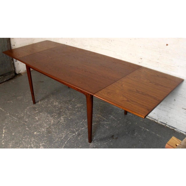 A versatile Mid-Century Modern dining table crafted in warm, richly grained teak. The design features discreet pull-out...