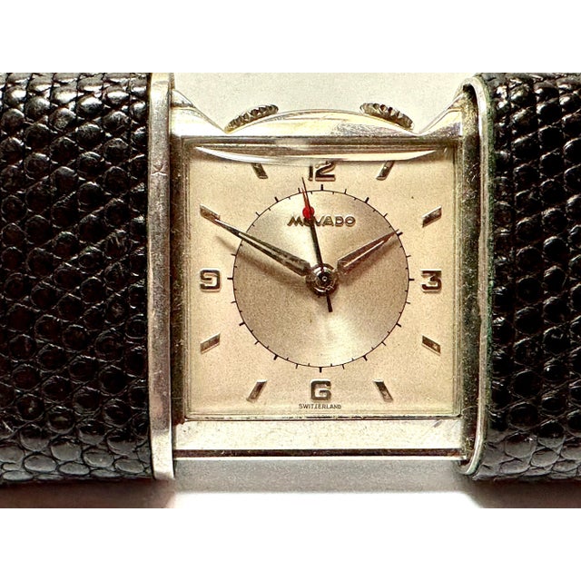 A lovely working Movado Ermeto traveling alarm clock. Covered in a lizard or faux lizard skin. The clock watch winds as...