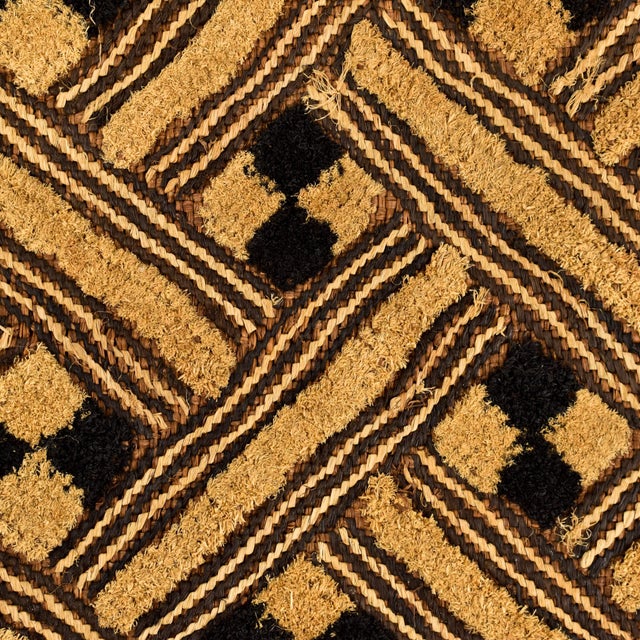 A square(ish) raffia textile made by the Kuba people of the Democratic Republic of the Congo. Decorated with geometric...