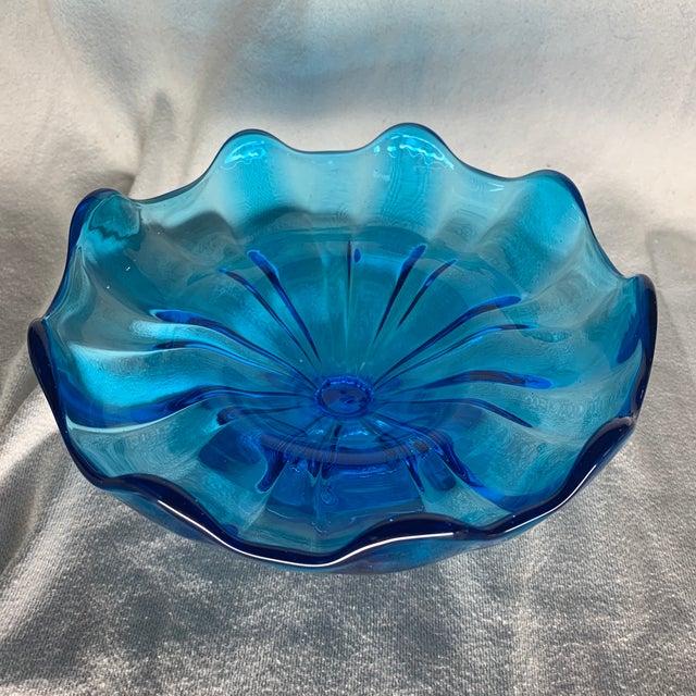 This is a vintage L.E. Smith peacock blue glass pedestal bowl featuring a striking ruffled handkerchief edge and ribbed...