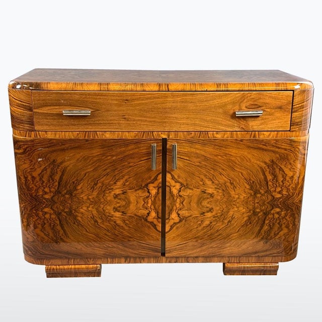 This elegant Art Deco chest of drawers features strong geometric lines softened by warm wood tones and a beautifully...