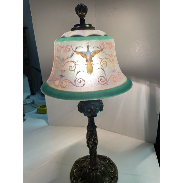 This vintage signed Pairpoint lamp shade with an ornate bronze base features a unique reverse painted design in shades of...