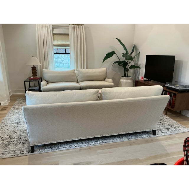 Two Lee Industries sofas upholstered in neutral ivory herringbone, with reversible down-filled cushions and matte nickel...