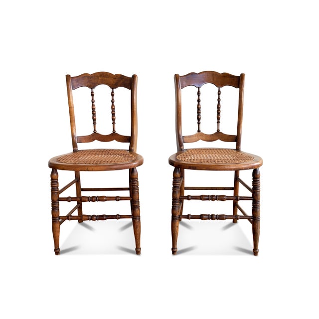 A graceful pair of spindle back cane chairs made in the 1940s era. The farmhouse chair pair feature two turned spindles,...