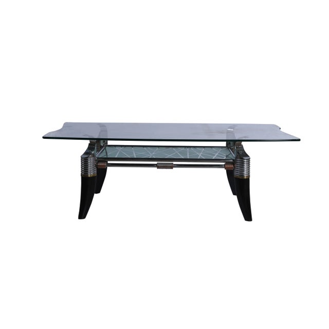 A very unusual Mid-Century Modern coffee table. It features ebonized legs in a faux horn motif, chrome detailing with a...