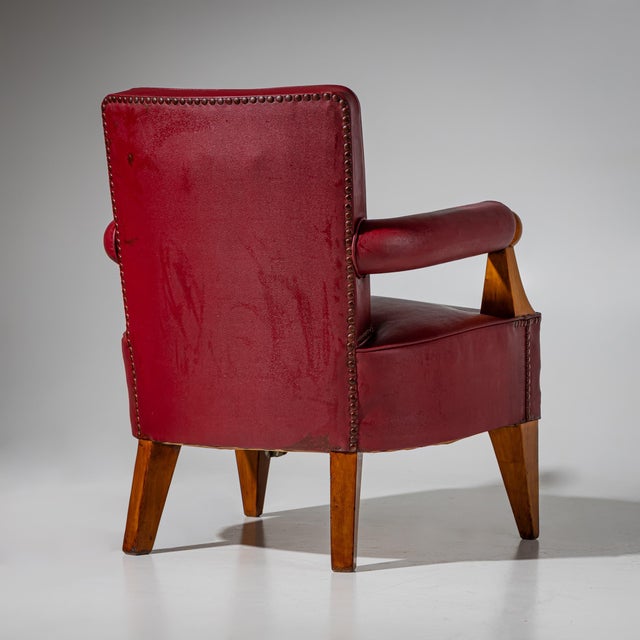 A pair of armchairs with tapered legs and armrests with wooden ball elements. The cover in a strong wine red color is...