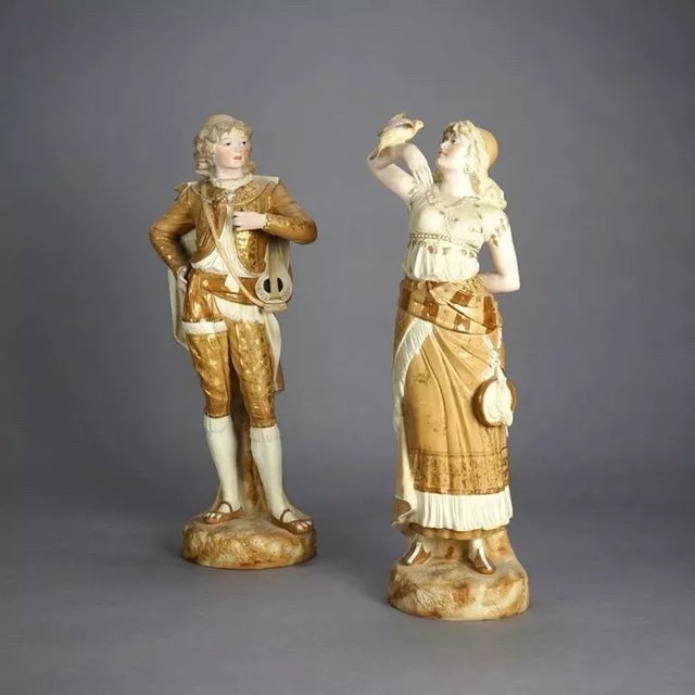 An Pair of Antique Continental Porcelain Bisque Statues of a Courting Couple dressed in their finest attire embellished...