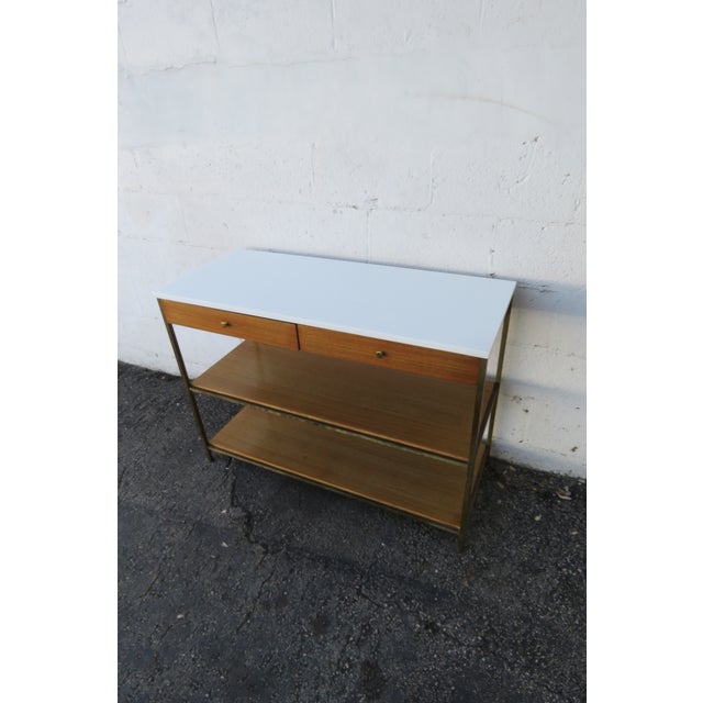 This Stunning Console Table is made of wood, mahogany, veneer, and metal. The piece was made by Paul MacCobb, the Irwin...