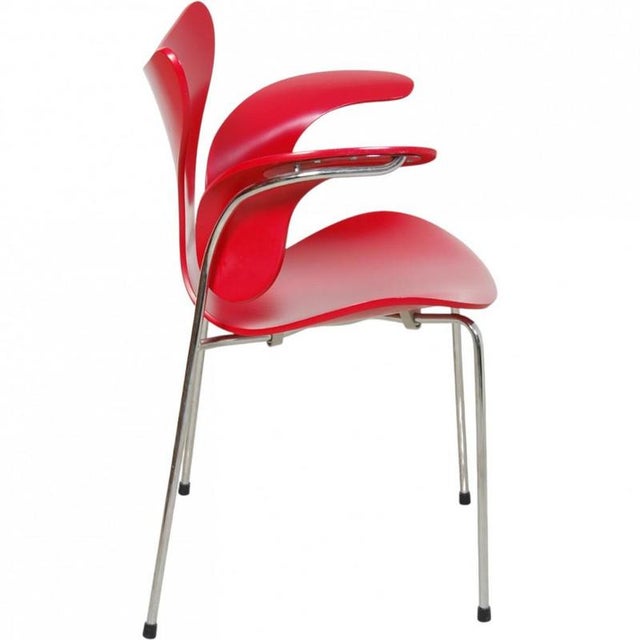 Arne Jacobsen Lily armchair, model 3208, with a red lacquered shell and chrome legs. The chair is from 2007 and appears in...