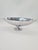 An elegant decorative bowl made of polished aluminum, designed in a modernist style. The model has an elongated,...