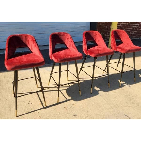 Set of four Eichholtz Avoiro bar stools with red velvet upholstery and a polished designer profile. A striking set for a...