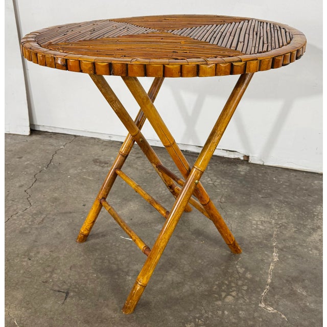 Vintage round collapsible rattan table. Features split reed top and scalloped edge. Sturdy with age wear.