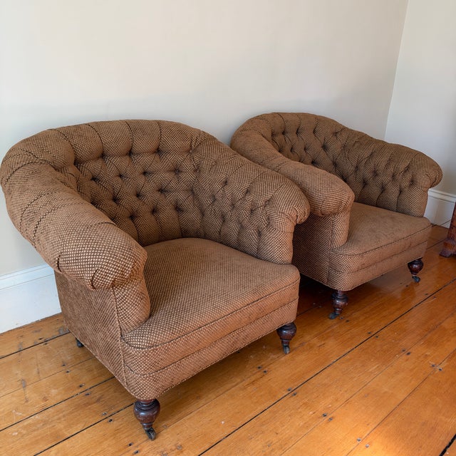 A pair of deep, generously scaled club chairs in the classic English country-house style. Each has a barrel back with...