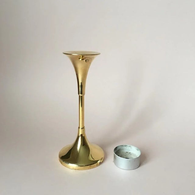 This heavy candle holder is made of solid brass. The piece is imprinted with a small blue crown to the bottom edge.