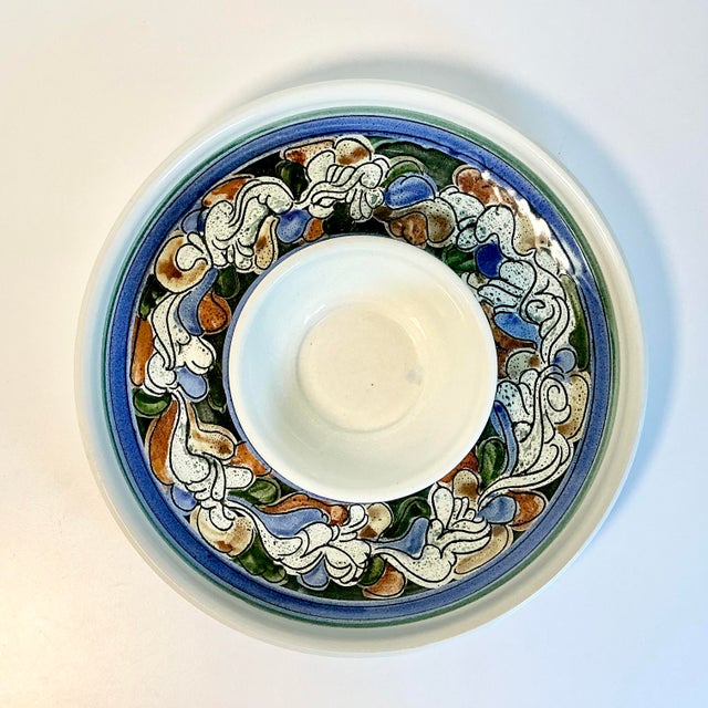 This 1990s Studio Potter piece is a large round chip and dip server. It has a blue, rust and dark green botanical style...