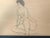 Gracious nude of a woman drawn with ink on craft paper. It is signed by the artist. The artwork sits in a simple black...