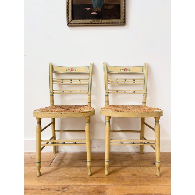 A completely charming pair of early 19th century rush seated bedroom chairs. Hand painted with lovely carved details, they...