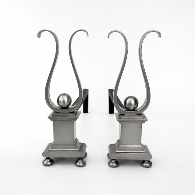Bold, structurally sound scroll-top pair of andirons. Substantial patinated plinth base resting upon balled-feet with a...