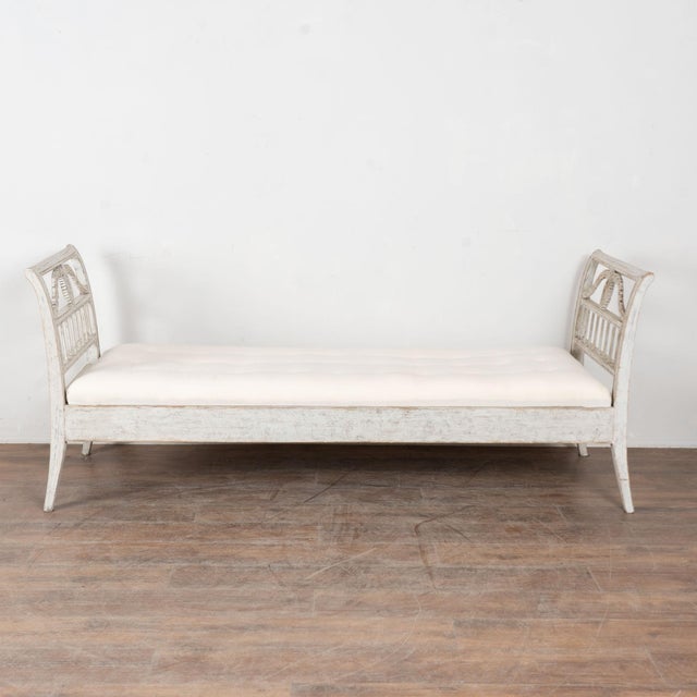 19th century Swedish Gustavian bench crafted in pine. This backless settee features graceful arms that curve slightly...