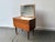 A compact and petite Mid-Century chest of drawers with mirror in rich-toned wood, supported on turned teak legs. It has...