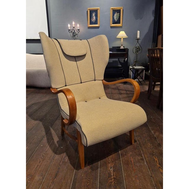 A rare Swedish Modern Wingback Chair, 1940s. Reupholstered in wool mix fabric with leather details. In beautiful...