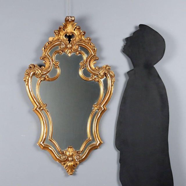 Carved and gilded wood mirror made in Italy in the mid-20th century. The molded frame is enriched with floral and leaf...