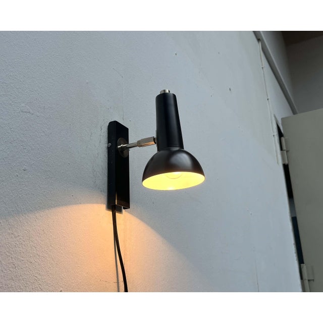 Simple wall light by Hustadt Leuchten. The light head has a simple spotlight shape and can be adjusted via a joint. The...
