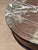 French walnut table with a circular marble top in mottled red and grey with white veining, set within a moulded frieze....