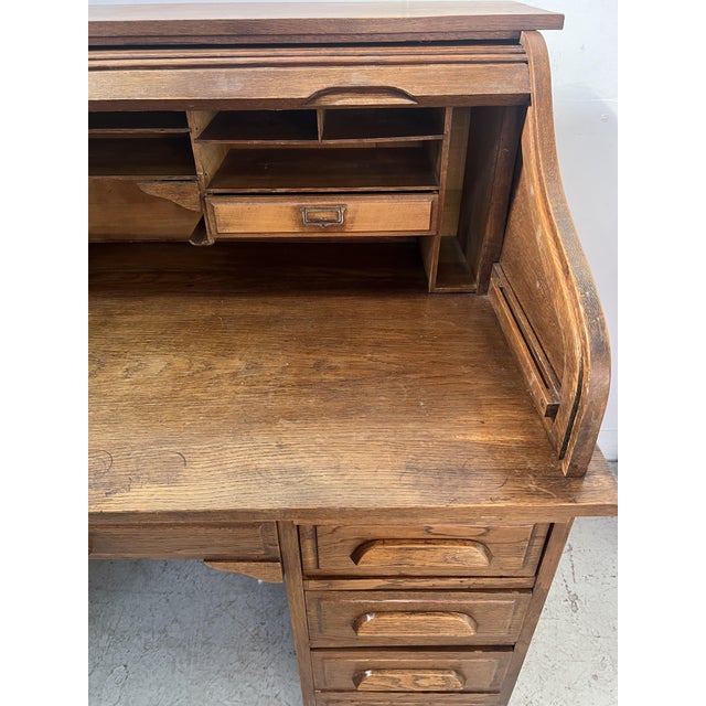 American-style solid oak desk Two four-drawer pedestals S-shaped roll-top top Interior compartmentalized with drawers and...