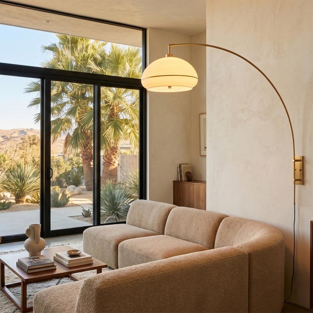 The Morelli Wall Mounted Arc Lamp is a Peter Morelli-designed modern lighting fixture with a weathered brass finish and a...