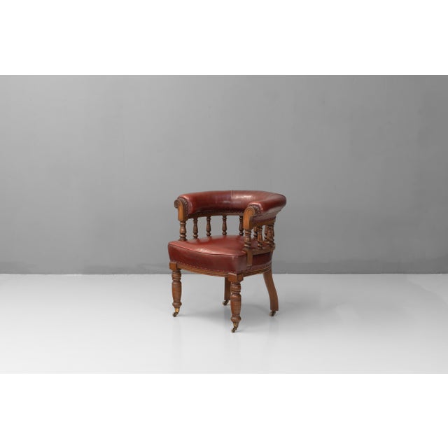 Walnut framed curved back office chair in aged red leather. Circa 1880.