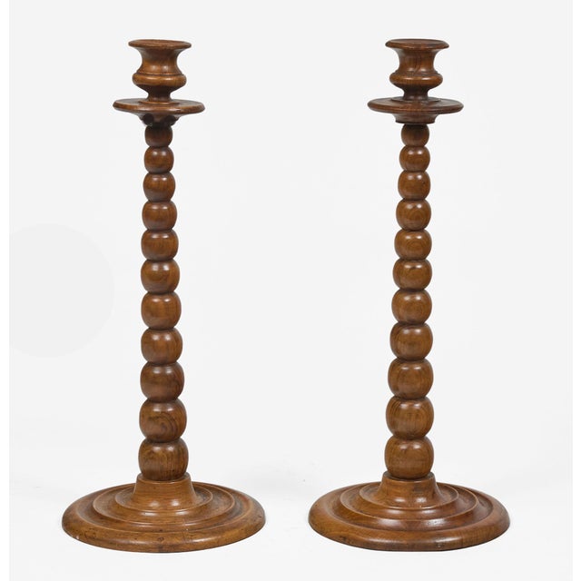 A very tall pair of Victorian bobbin turned walnut candlesticks with turned candle cups and turned round bases.