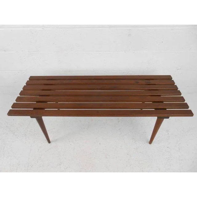 This beautiful vintage modern slat bench is made of solid walnut and features tapered legs. This unique mid-century bench...