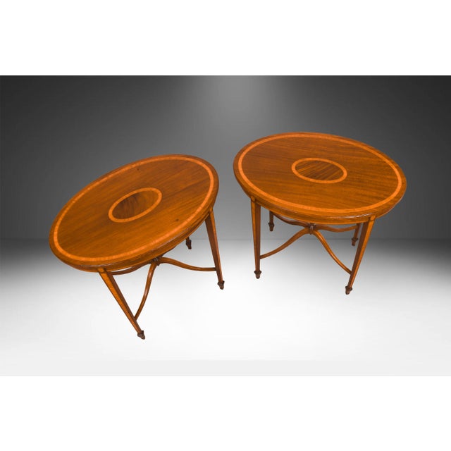 Pair of Mahogany oval side tables accented with satinwood inlay and borders early 20th Century. The pair is finished on...