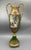 Elegant vintage decorative urn featuring rich green panels, ornate gold-tone detailing, and classical figural scenes. The...