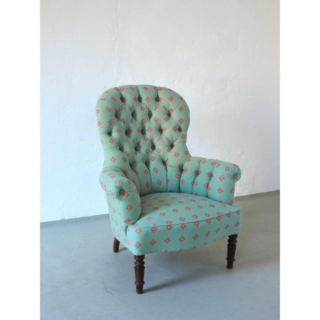 Vintage Victorian-style armchair with a high button-tufted backrest and elegant scroll arms. Upholstered in washed blue-...