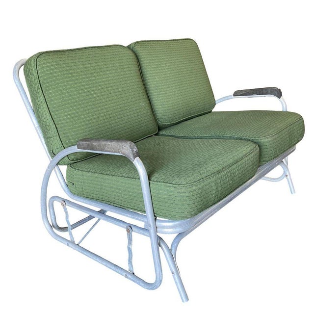 Pair of Art Deco patio lounge settees both consisting of an aluminum tubular frame with decorative streamlined speed arms....