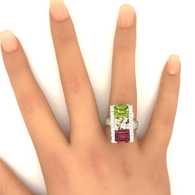 A bold ring showcasing an emerald-cut tourmaline with a captivating mint-green and pink hue. The tourmaline is...