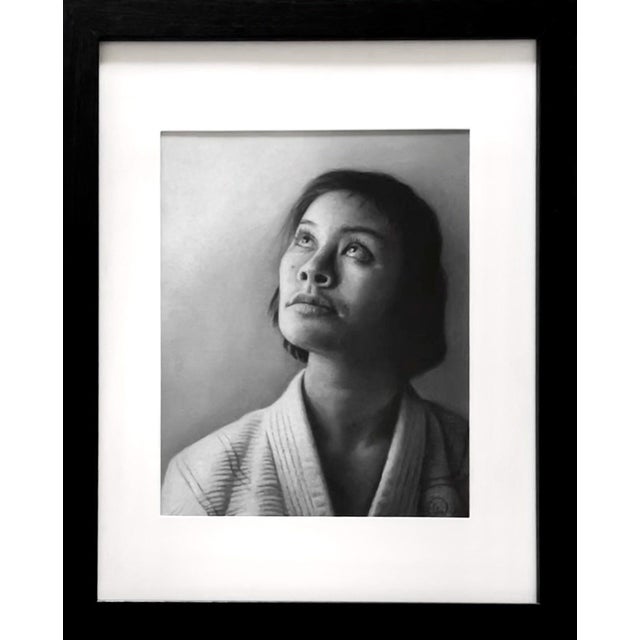 This charcoal work captures a moment of introspection as a young woman gazes upward, her expression a blend of hope and...