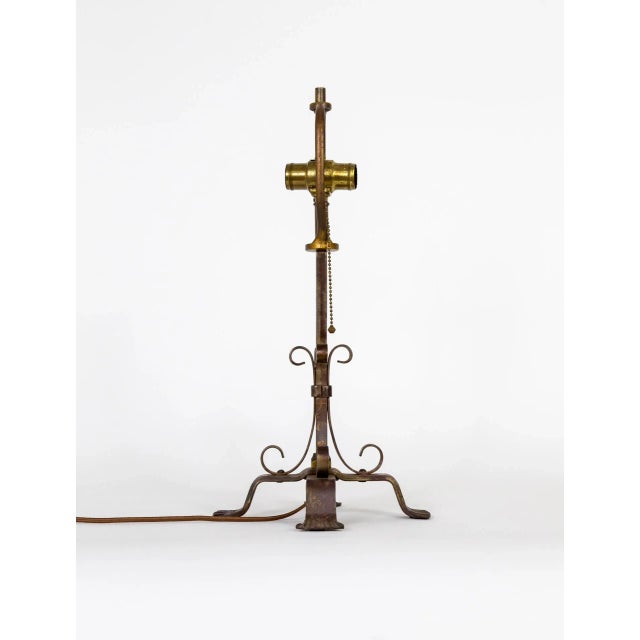 An antique wrought iron table lamp with 4 legs and C-curves banded to the stem. With 2 sockets, a pull chain switch, and a...