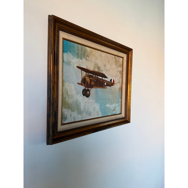 Charming vintage aviation-themed oil on canvas painting depicting a classic early 20th-century aircraft soaring through...