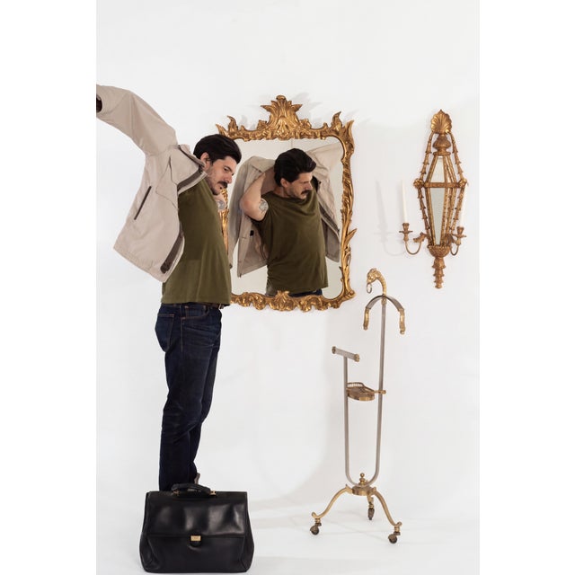 An elegant Italian giltwood mirror and coordinating pair of mirrored candle sconces, distinguished by their finely carved...