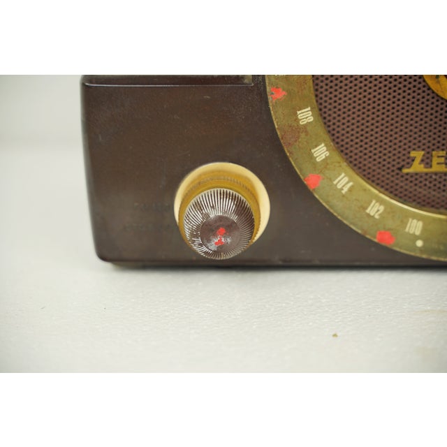Vintage portable AM/FM tube radio with a brown bakelite case, polished brass and plastic knobs, and channel ring. It was...