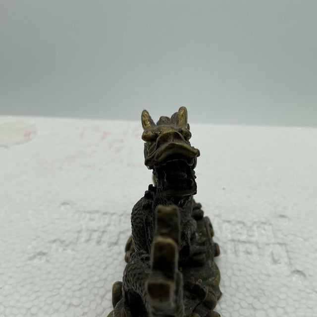 Charming vintage Chinese bronze sculpture depicting a traditional dragon emerging from stylized waves. The highly detailed...
